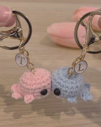 two crocheted whale keychains in pink and blue
